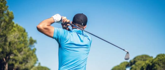 Male golf player swinging golf club.